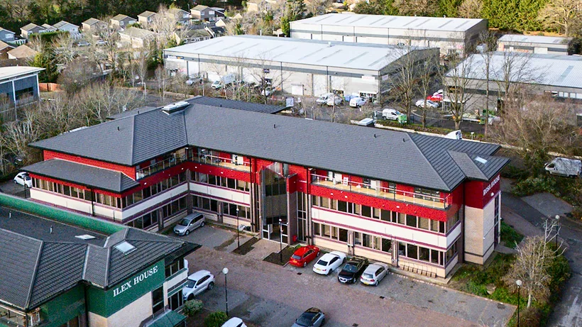Drone: red-trimmed office campus, parking and trees, drone property photography London