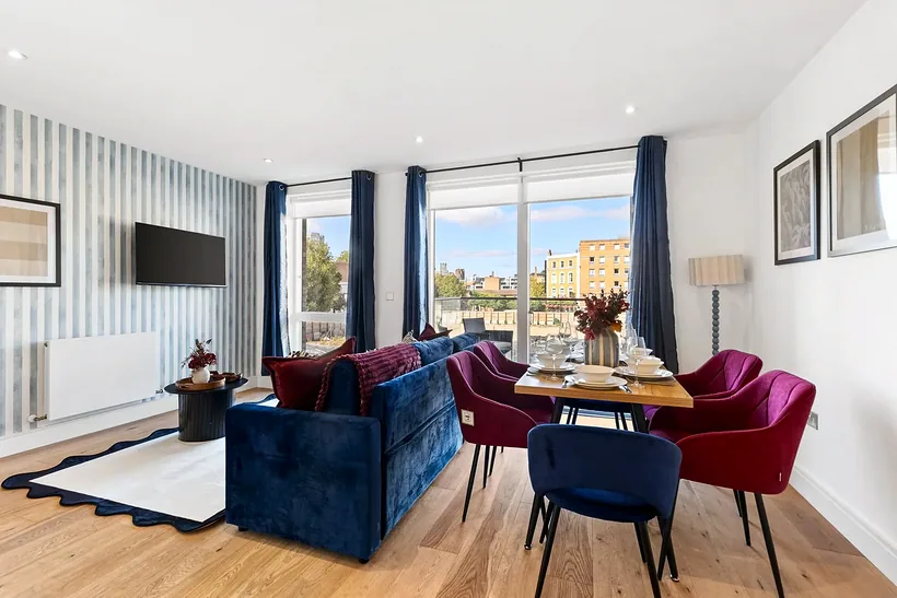 Living and dining room with velvet chairs and a city view, Airbnb photography London
