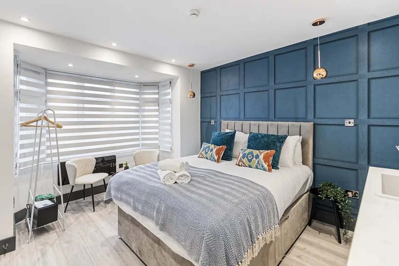 Bedroom with a blue panelled feature wall, Airbnb photography London