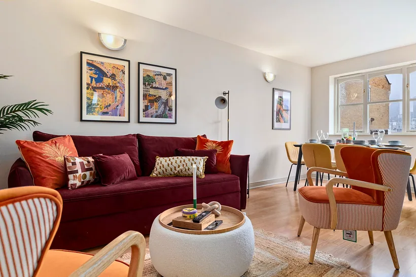 Burgundy velvet sofa living, orange accents, art wall, Airbnb photography London