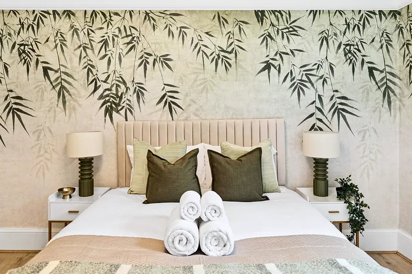 Leaf-mural bedroom with olive cushions, Airbnb photography London