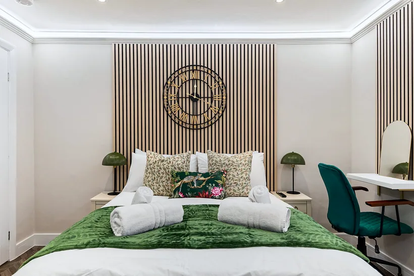 Emerald bedding, slatted wall and clock, Airbnb photography London