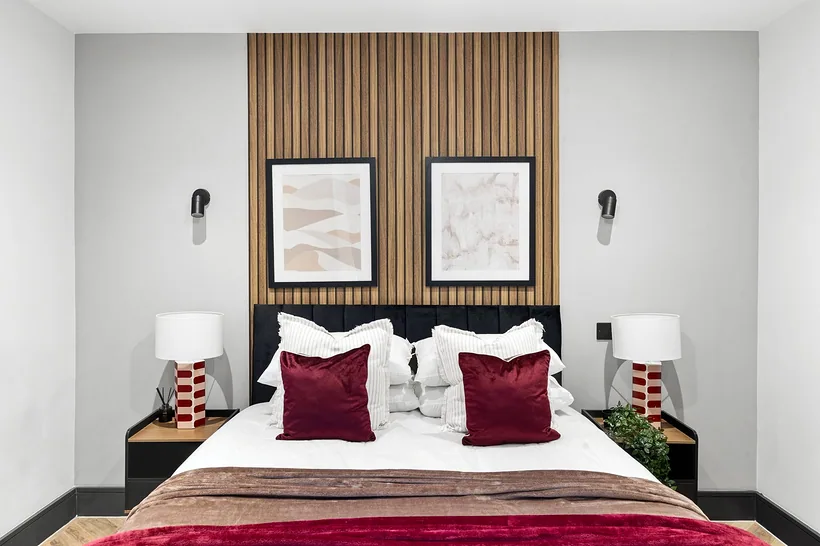 Symmetrical slatted-wall bedroom with crimson accents, Airbnb photography London