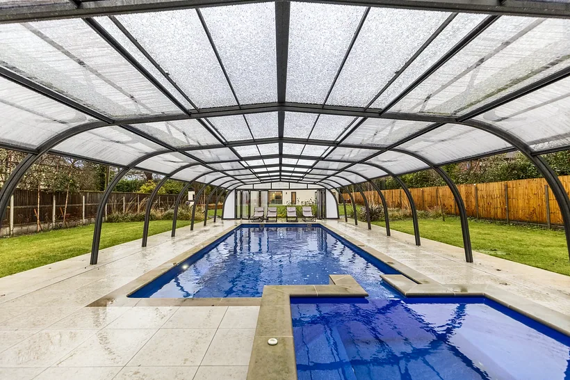 Indoor pool under curved glass enclosure, mosaic tiles, Airbnb photography London