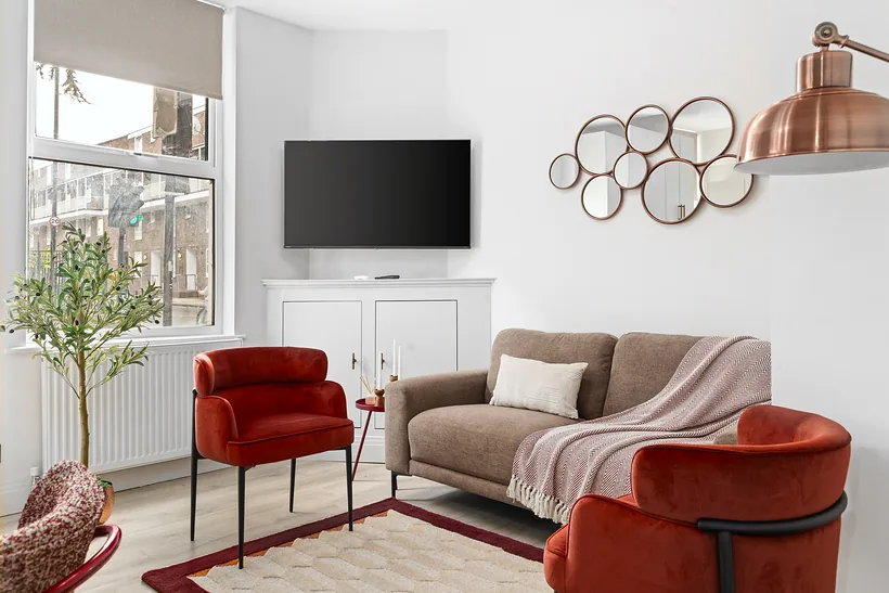 Living room with rust velvet chairs and a copper floor lamp, Airbnb photography London