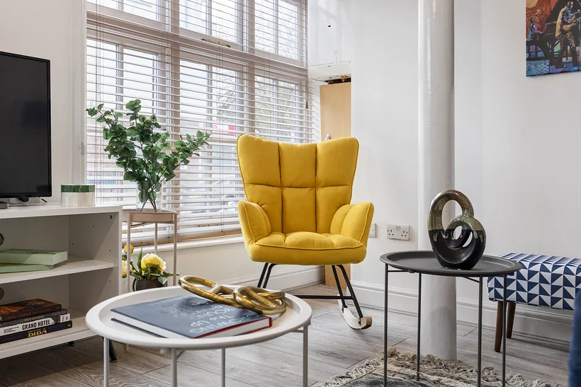 Yellow armchair by tall shuttered windows, Airbnb photography London
