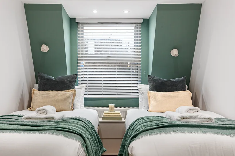 Twin bedroom with green walls and matching throws, Airbnb photography London