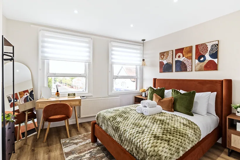 Bedroom with a tan velvet bed and a small desk, Airbnb photography London