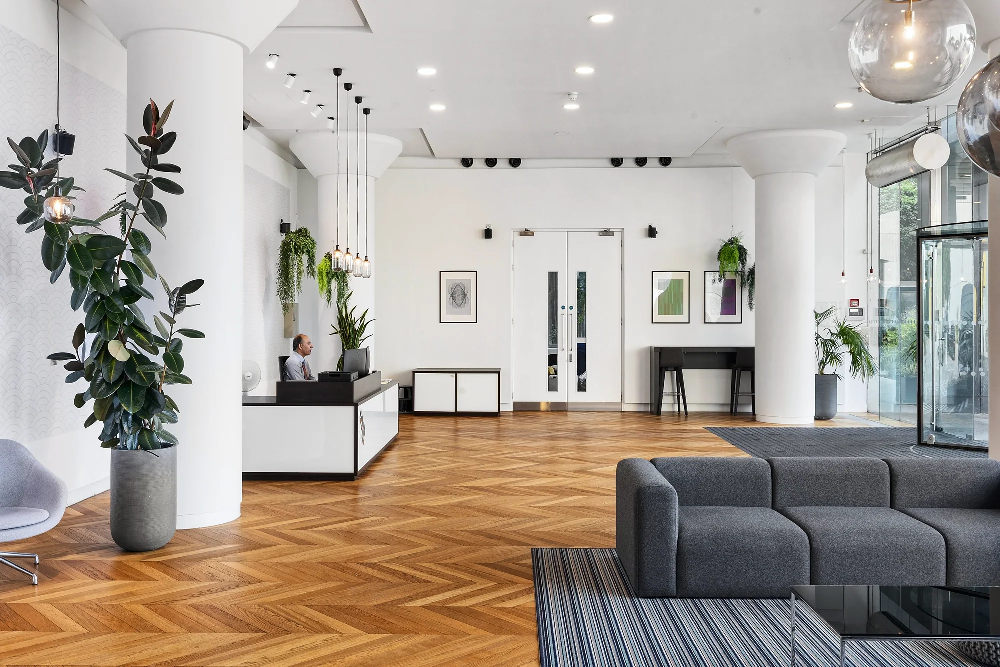 Reception with a herringbone floor and grey sofa, commercial photography London