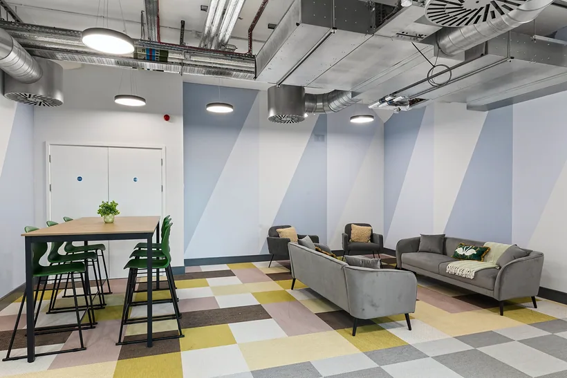 Breakout area with patterned carpet and high tables, commercial photography London