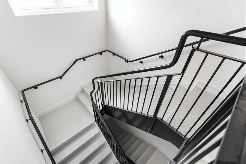 Bright white stairwell with a black steel balustrade, developer photography London