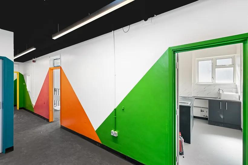 Corridor with bold green and orange graphic walls, developer photography London