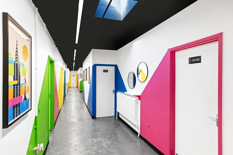 Communal corridor with coloured door surrounds and artwork, developer photography London