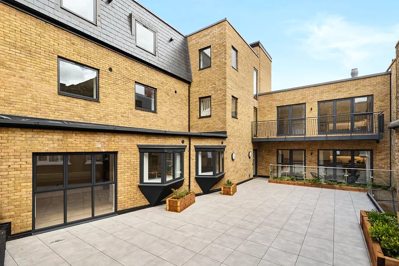 New-build courtyard development, brick and glazing, blue sky, developer photography London