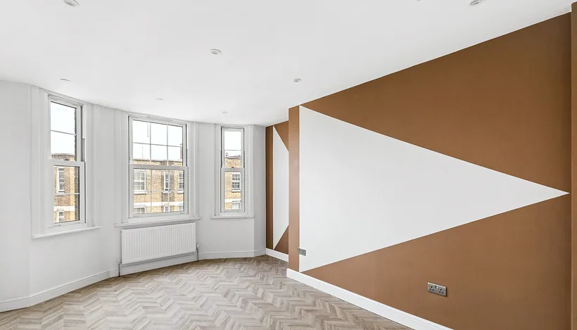 Bold geometric terracotta wall mural in bright HMO room, developer photography London