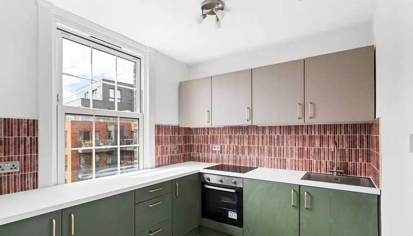 Sage shaker kitchen with terracotta brick-tile splashback, developer photography London