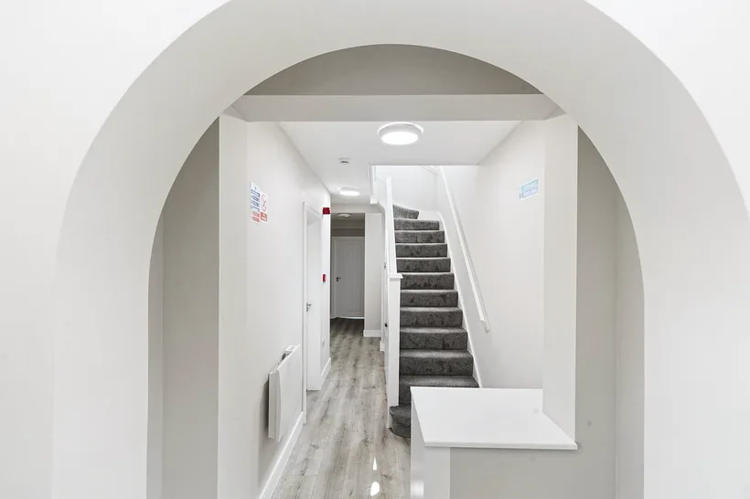 Arched hallway framing staircase, elegant composition, developer photography London