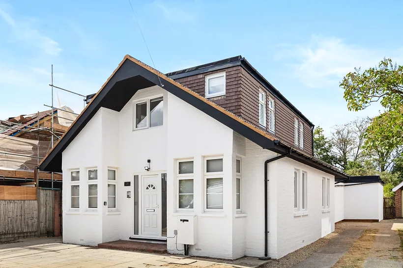 White-rendered gabled house with dormer, crisp sky, developer photography London