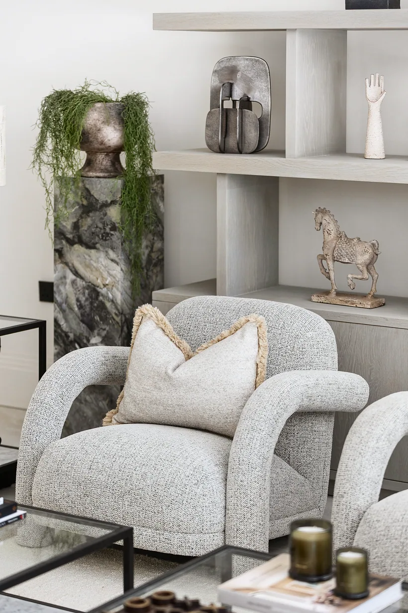 Bouclé armchairs with styled shelving and a trailing plant, interior photography London