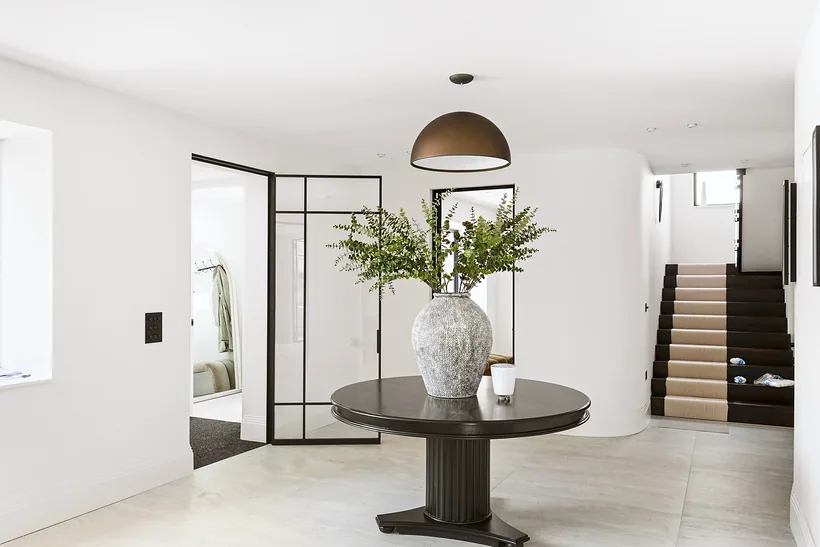 Bright hallway with a round pedestal table and staircase, interior photography London