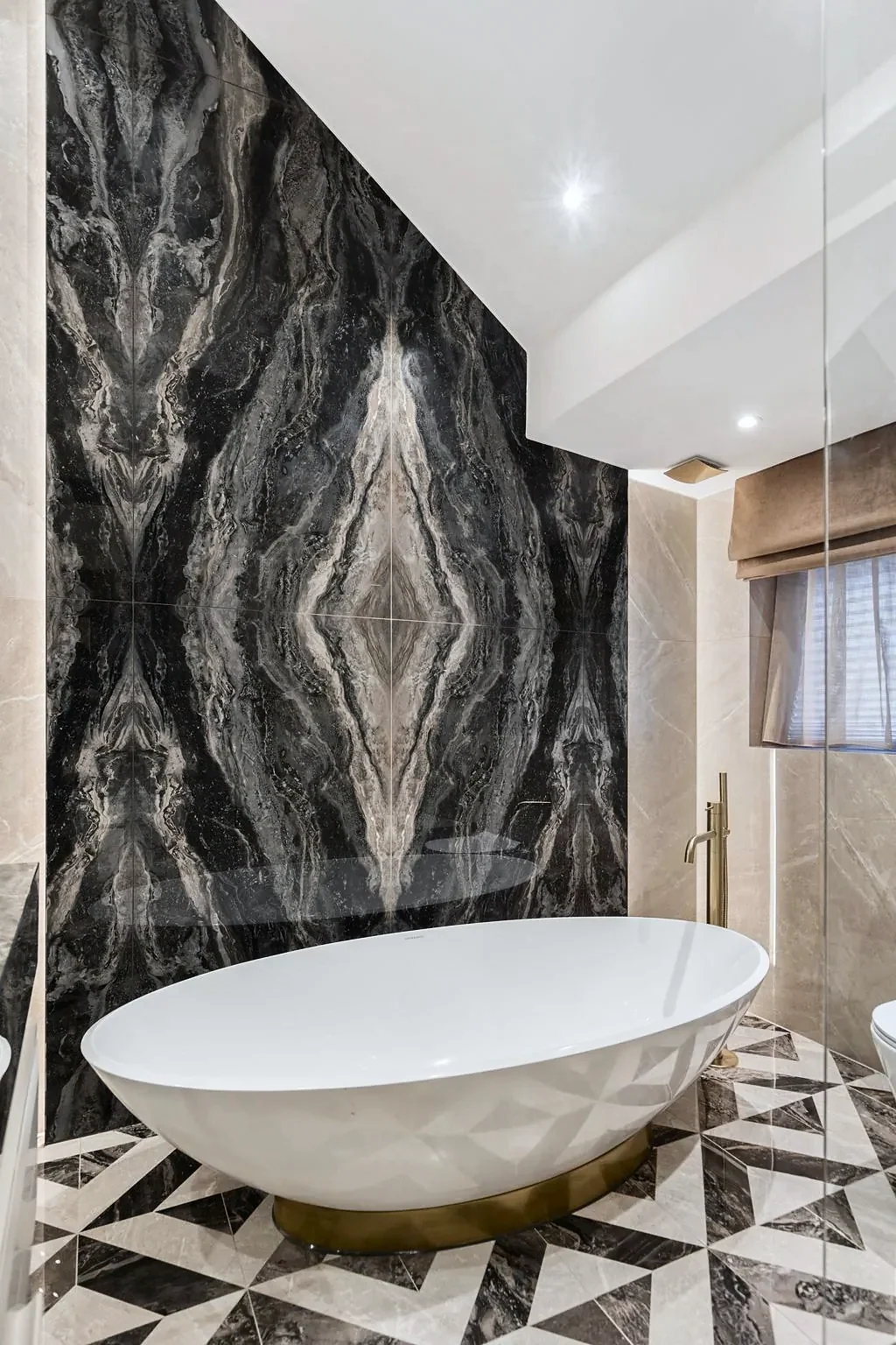 Freestanding bath against a book-matched marble wall, interior photography London