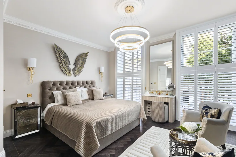 Bedroom with a tiered chandelier and plantation shutters, interior photography London