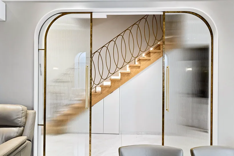 Arched glass doors framing a brass staircase, interior photography London
