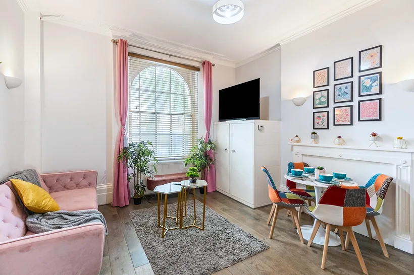 Pink and gallery-wall living, bright arched window, interior photography London