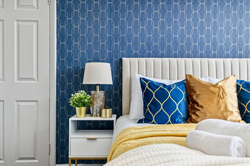 Navy geometric wallpaper with mustard cushions, interior photography London