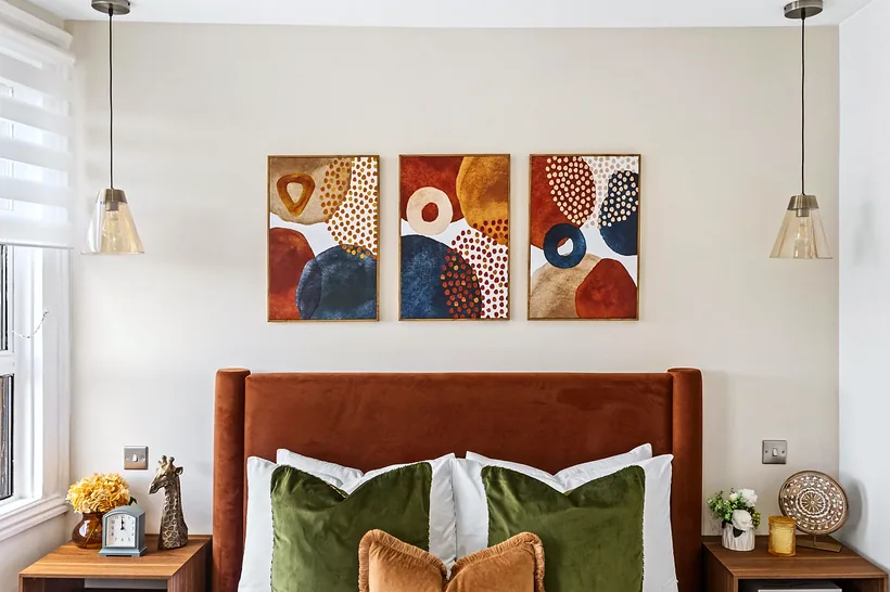 Styled bedroom: rust velvet headboard, abstract triptych, interior photography London