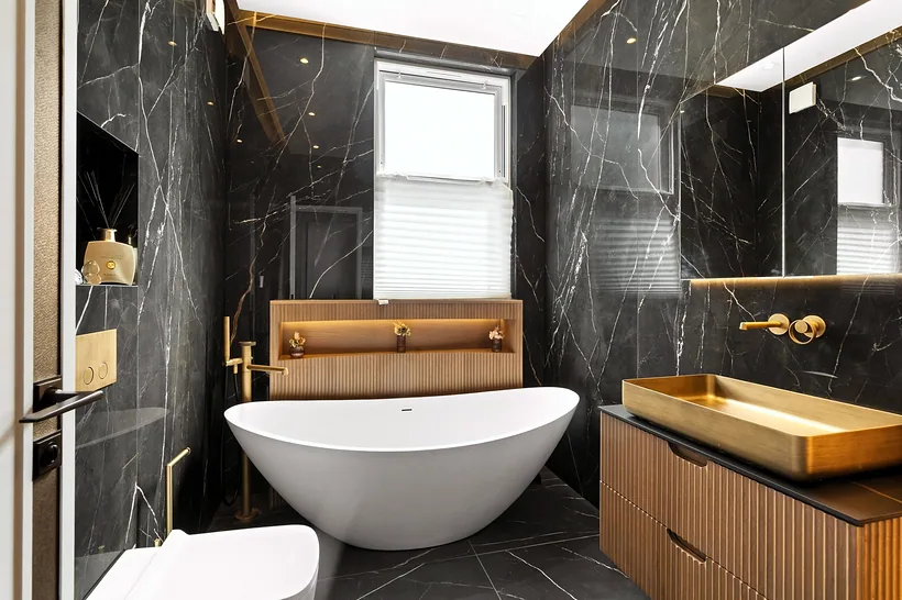 Black marble bathroom with freestanding tub and brass basin, interior photography London