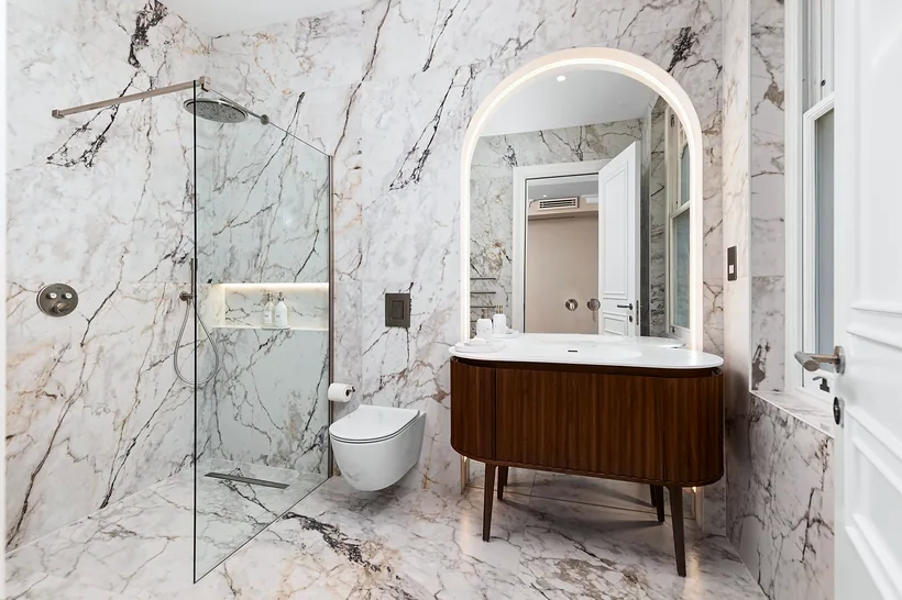 Calacatta Viola bathroom with arched mirror and walnut vanity, interior photography London