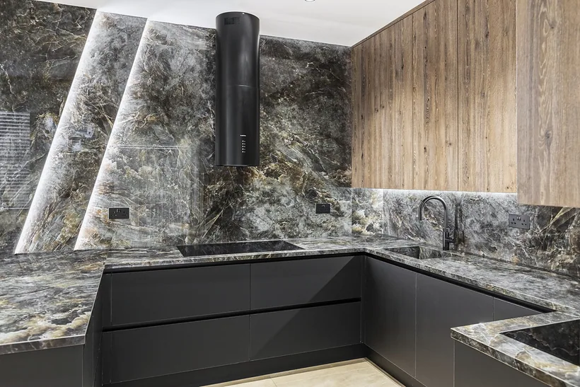 Dark stone kitchen with lit splashback, kitchen photography London