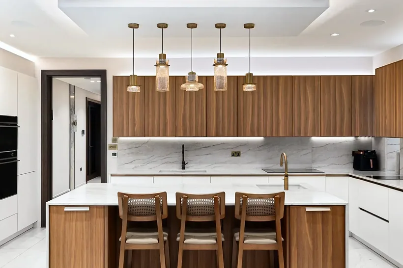 Walnut kitchen with a breakfast bar and glass pendants, kitchen photography London