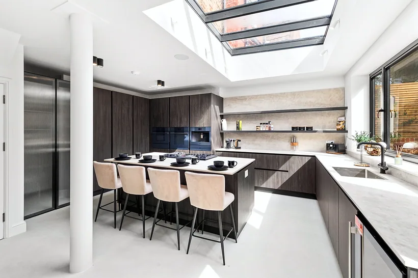 Skylit open-plan kitchen, dark units, island and dining, kitchen photography London