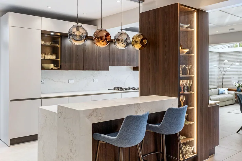 Stone breakfast bar with copper pendants and blue stools, kitchen photography London