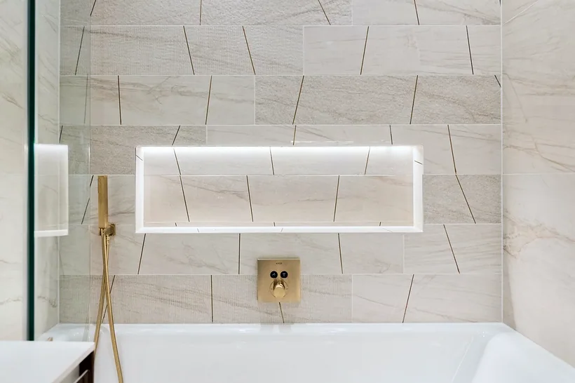 Lit niche bath with brass fittings, stone tiles, kitchen photography London
